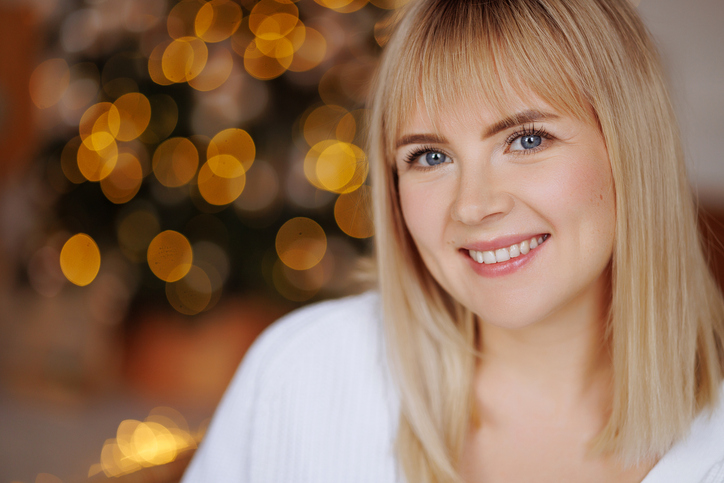 Smiling woman with glowing skin with blurred festive lights in the background