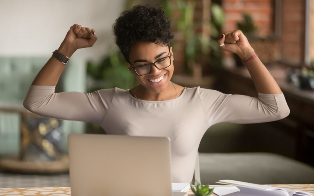 A woman celebrating her rewards while on her computer