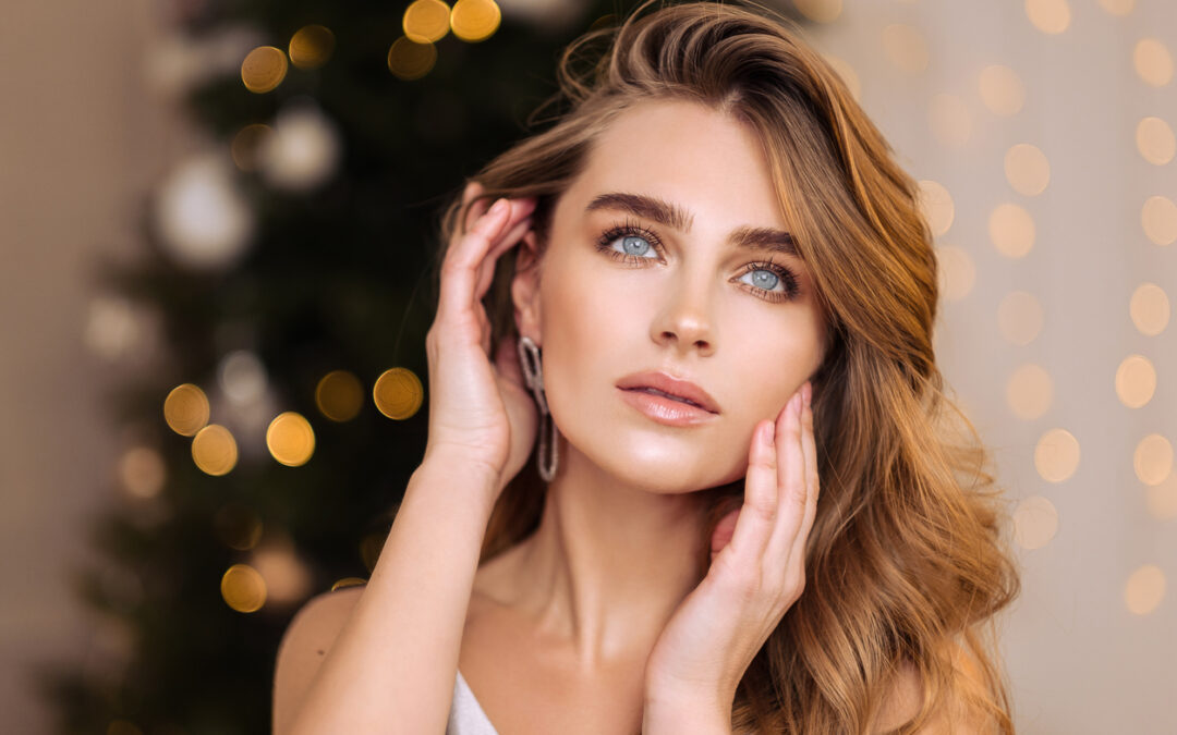 A woman in front of a Christmas tree admiring her smooth skin