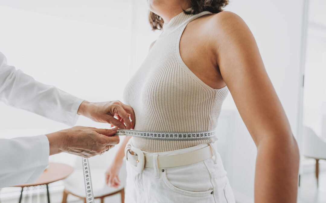 A woman at a weight loss clinic measuring her abdomen size