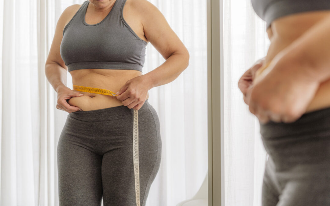 Woman in sports clothing measuring her waist